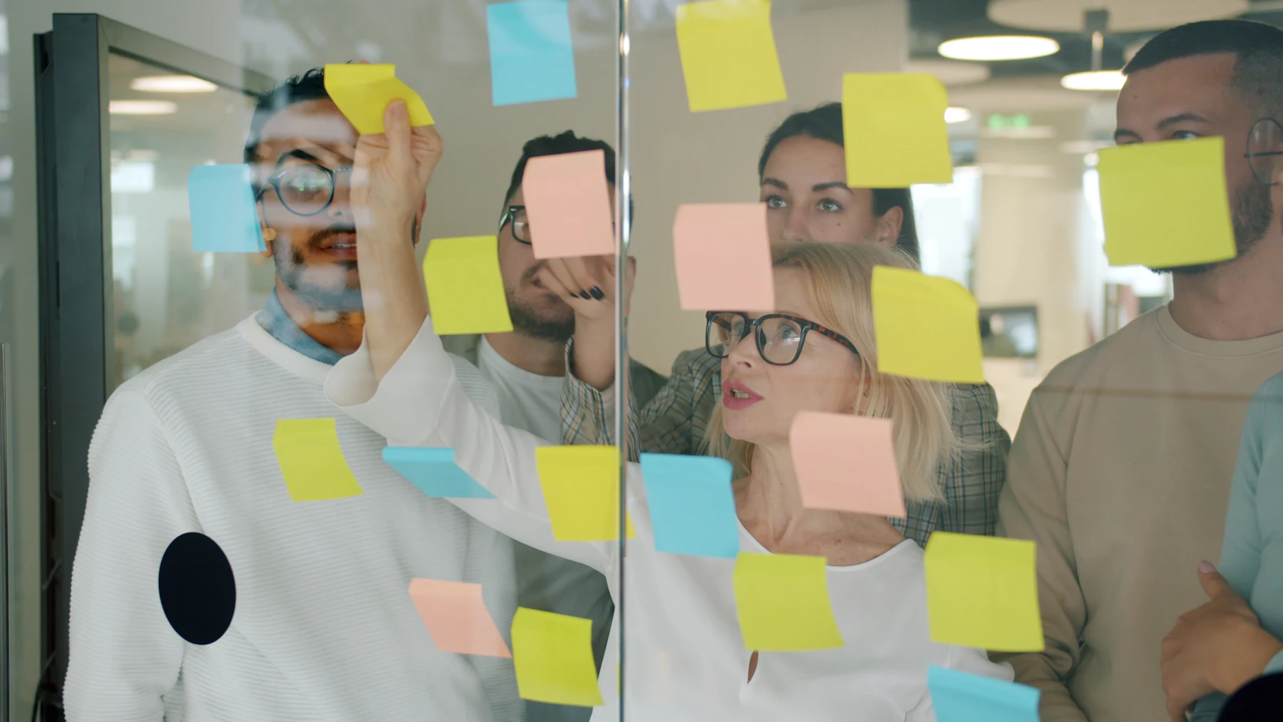 A team planning work with sticky notes on a glass wall